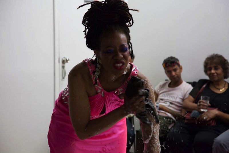 Ayana Evans wears a hot pink dress as she suds up her skin with a sponge